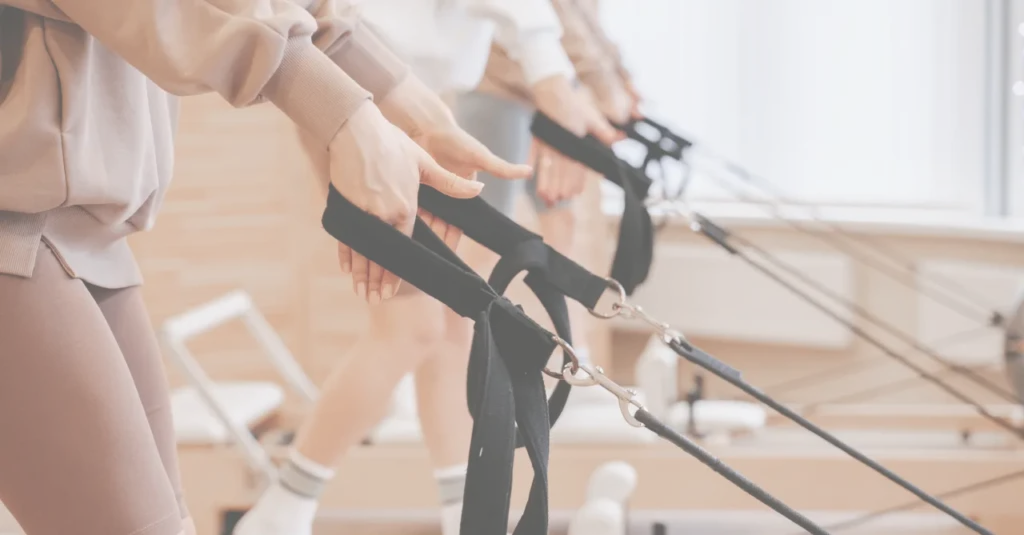 Close-up of clients using Pilates reformer straps during a class at Revival Pilates Studio, connected to membership and mailing list signup.