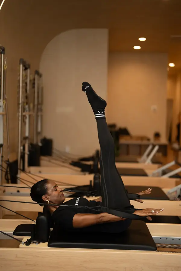 Woman practicing reformer Pilates at Revival Pilates studio in Houston, emphasizing classical technique and whole-body wellness.